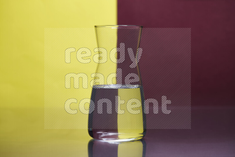 The image features a clear glassware filled with water, set against yellow and dark red background