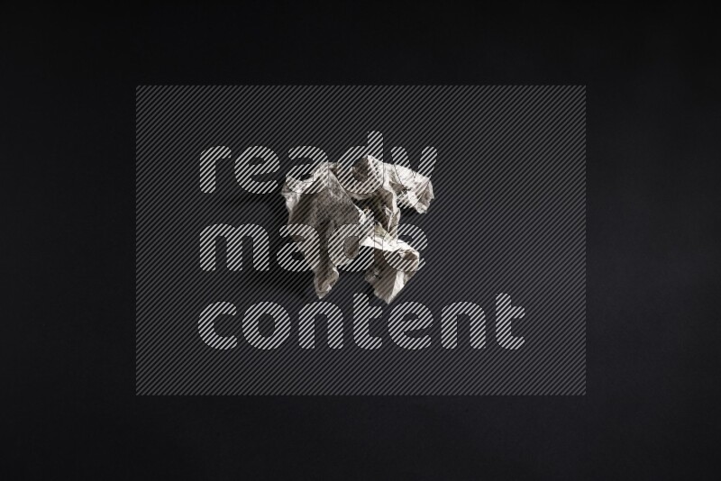 Crumpled newspaper sheet on black background