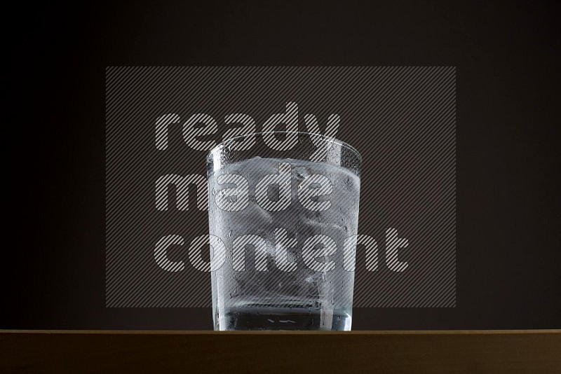 Low angle shot of a glass of water and ice on grey background