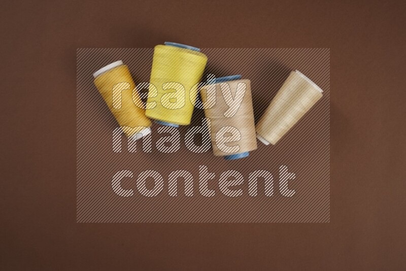 A yellow collection of sewing and tailoring tools arranged on a brown background