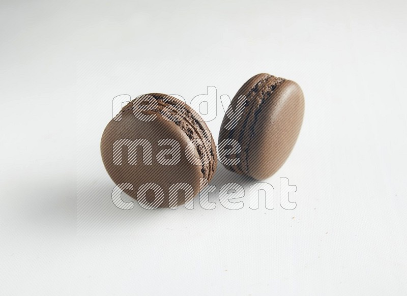 45º Shot of two Brown Dark Chocolate macarons on white background