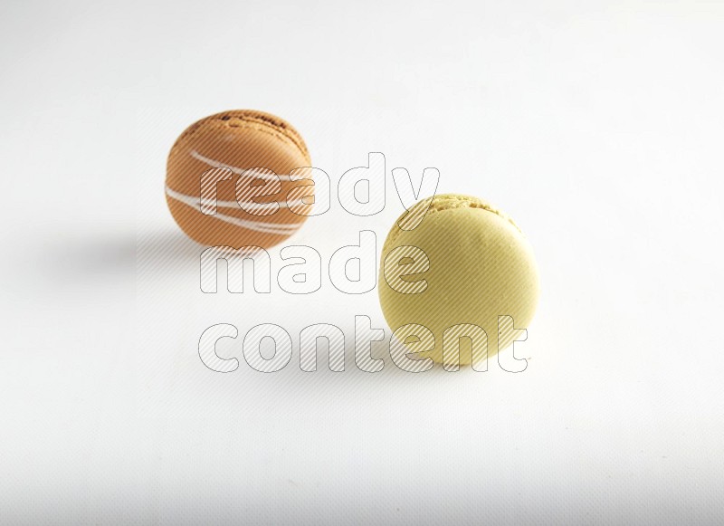 45º Shot of of two assorted Brown Irish Cream, and Yellow Lime macarons on white background