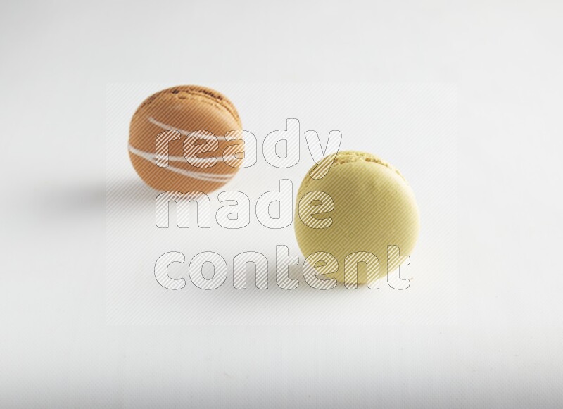 45º Shot of of two assorted Brown Irish Cream, and Yellow Lime macarons on white background
