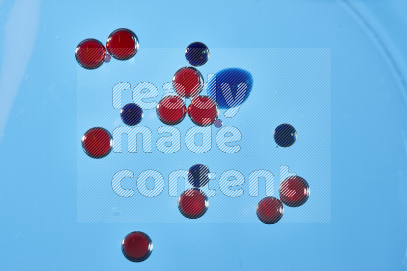 Close-ups of abstract red and blue watercolor drops on oil Surface on blue background