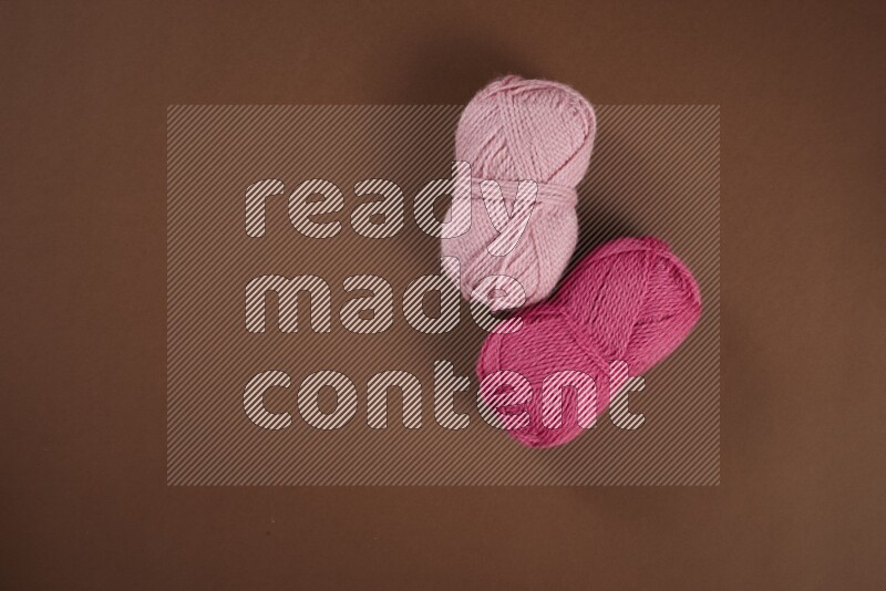 A pink collection of sewing and tailoring tools arranged on a brown background