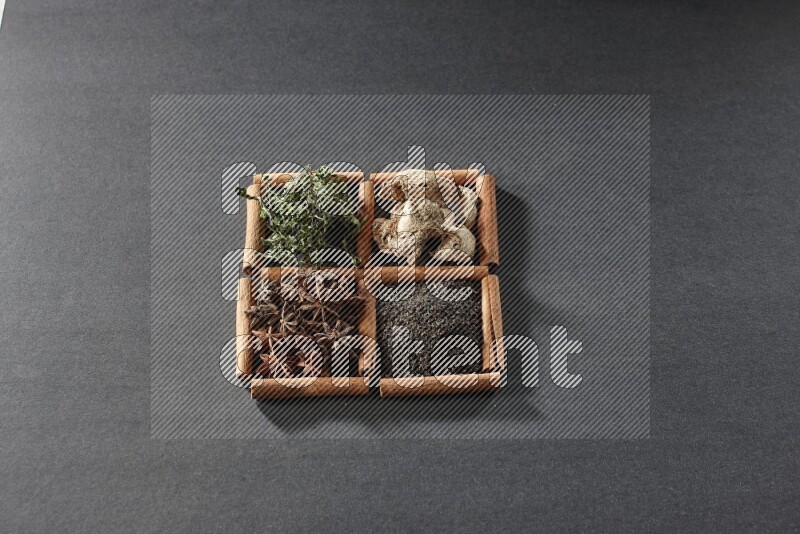 4 مربعات من عيدان القرفة ممتلئة بالشاي الأسود والزنجبيل المجفف والنعناع المجفف واليانسون النجمي على أرضية سوداء