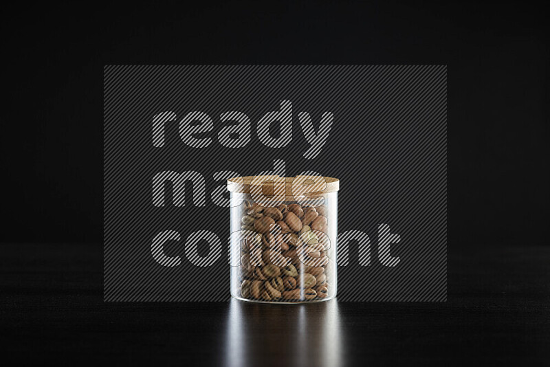 Fava beans in a glass jar on black background