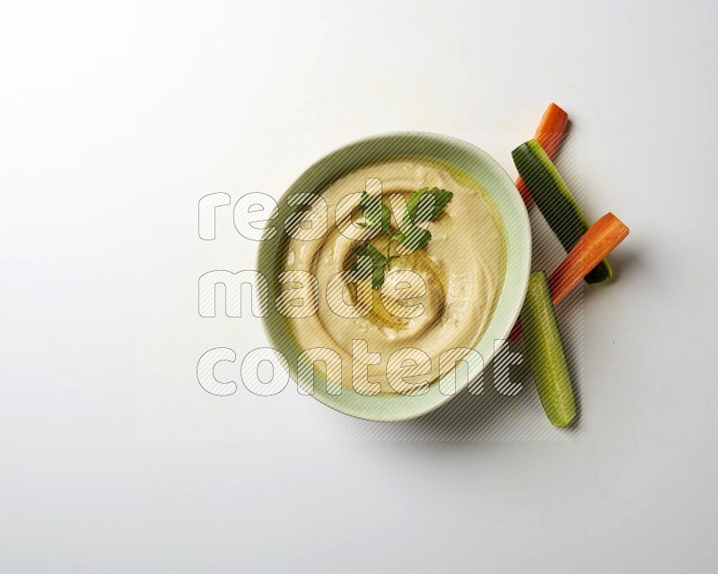 Hummus in a green plate garnished with parsley on a white background