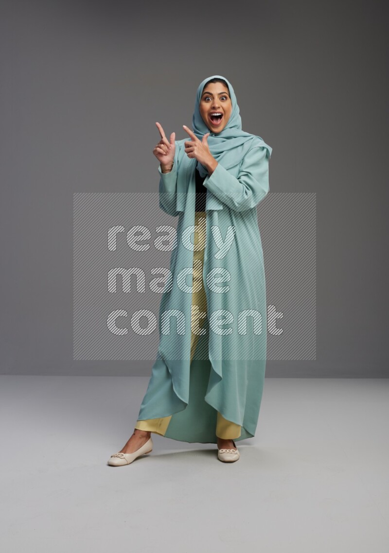 Saudi Woman wearing Abaya standing interacting with the camera on Gray background