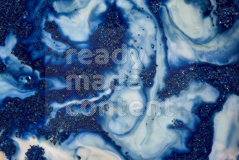A close-up of sparkling blue glitter scattered on swirling blue and white background