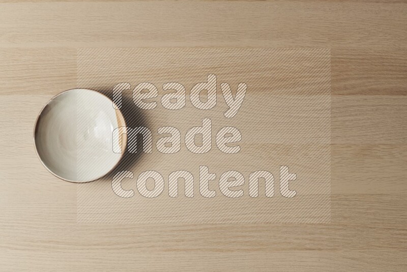 صحن فخاري متعدد الألوان على خلفية خشبية فاتحة