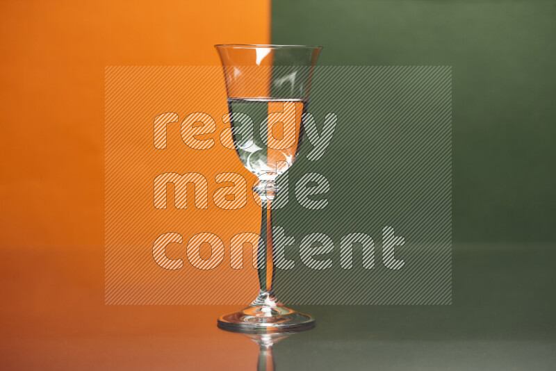 The image features a clear glassware filled with water, set against orange and dark green background