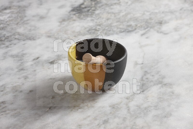 Multicolored pottery bowl with wooden honey dipper in it on grey marble background