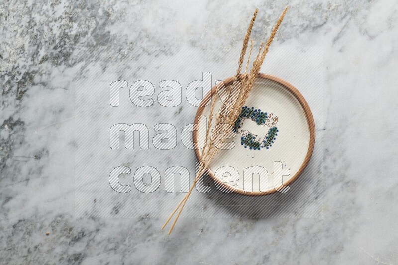 Wheat stalks on decorative pottery plate on grey marble background