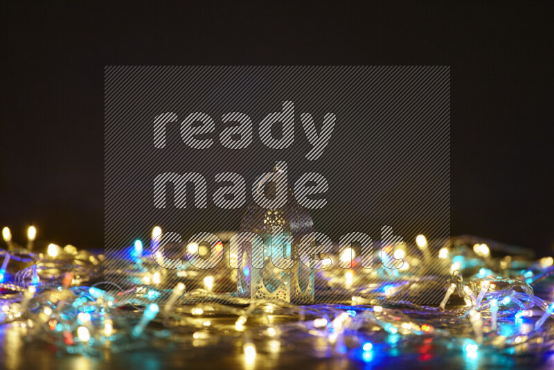 A traditional ramadan lantern surrounded by glowing fairy lights in a dark setup