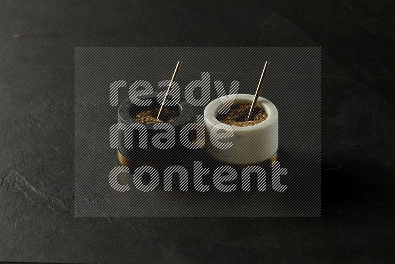 black and white round marble containers filled with herbs on gray textured countertop