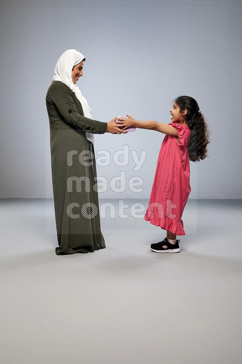 A girl giving a gift to her mother on gray background