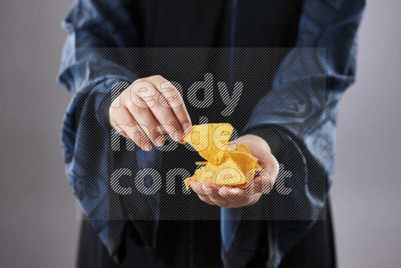 Woman in abaya holding different kinds of snacks in different positions