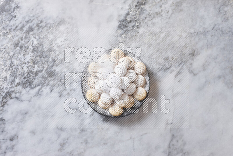 كحك في صحن فخار أسود على خلفية رخام رمادي