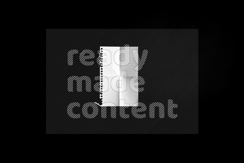 Folded notebook sheet on black background