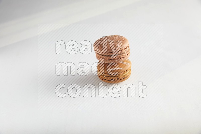 45º Shot of of two assorted Brown Irish Cream, and Brown Hazelnuts macarons on white background