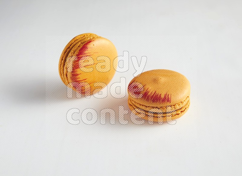 45º Shot of two orange Exotic macarons on white background