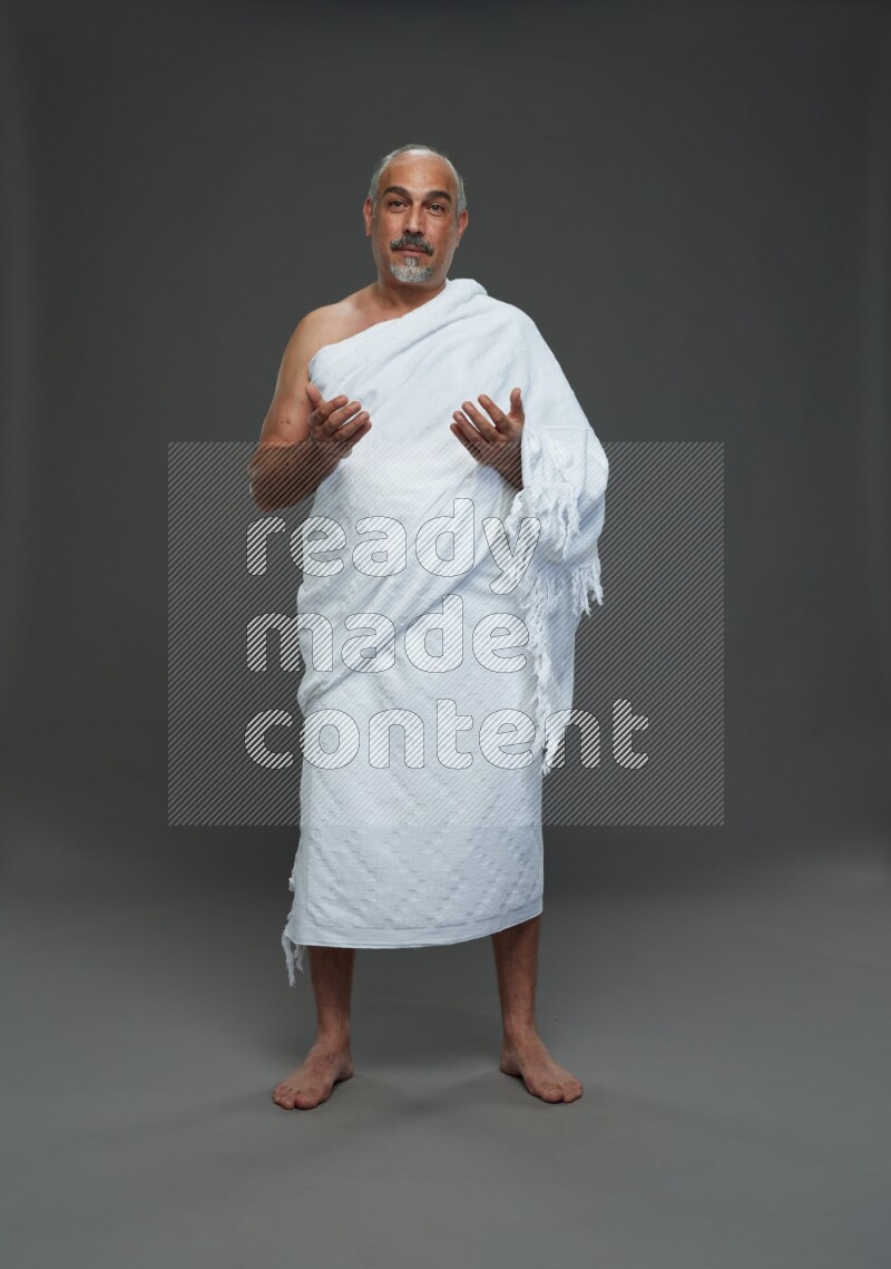 A man wearing Ehram Standing dua'a on gray background