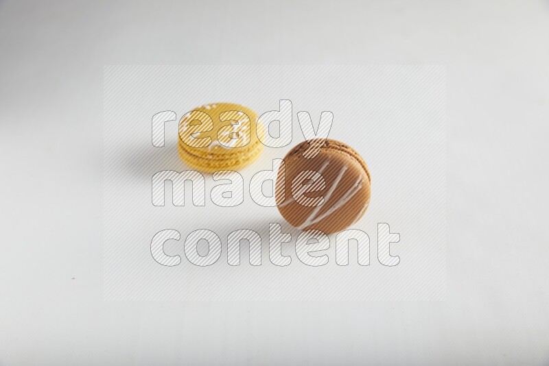 45º Shot of of two assorted Brown Irish Cream, and Yellow Piña Colada macarons on white background