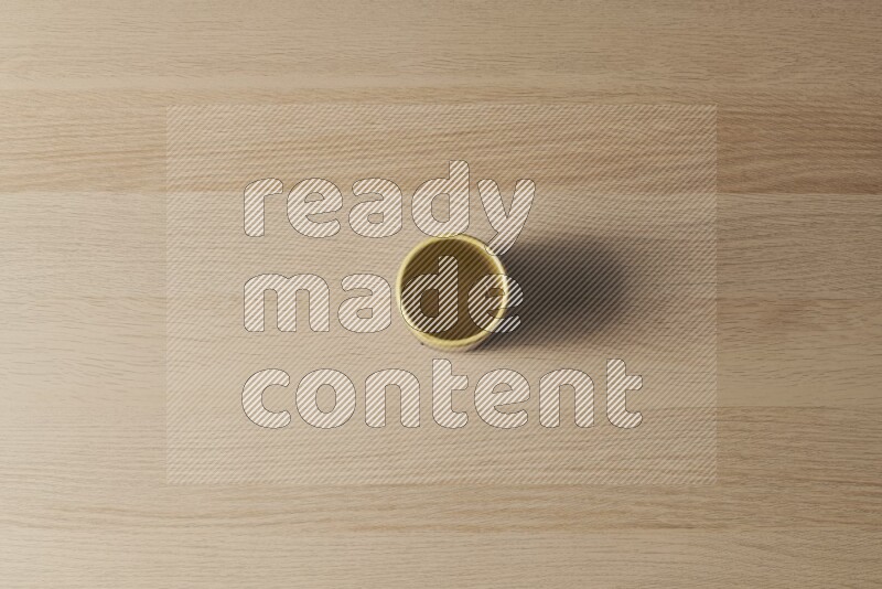 A multicolored pottery cup on light wooden background