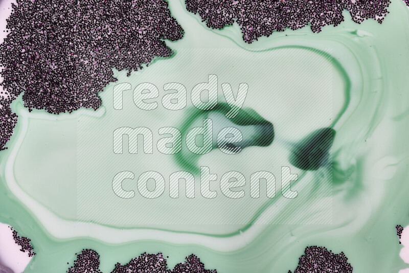 A close-up of sparkling purple glitter scattered on swirling green and white background
