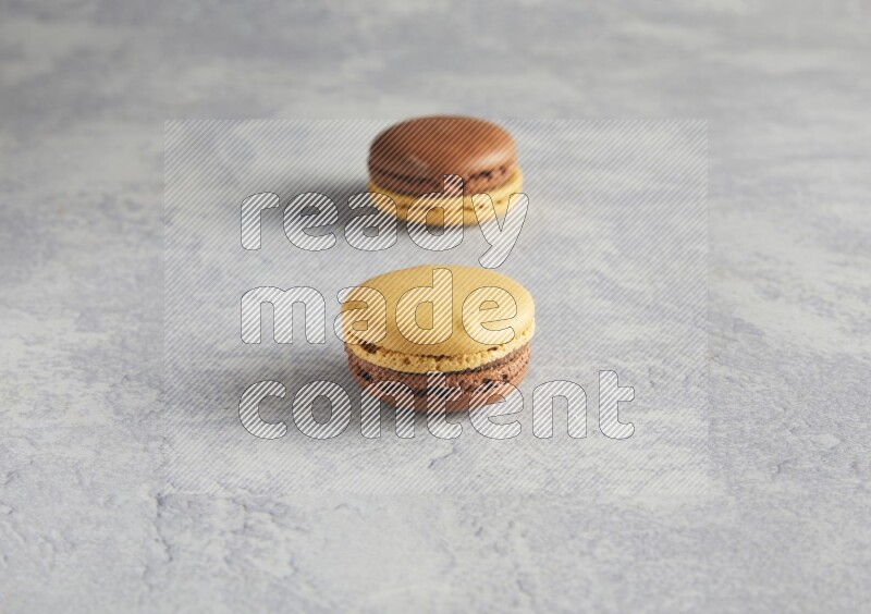 45º Shot of two Yellow and Brown Chai Latte macarons r on white  marble background