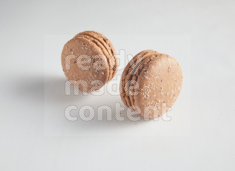 45º Shot of two Brown Hazelnuts macarons on white background