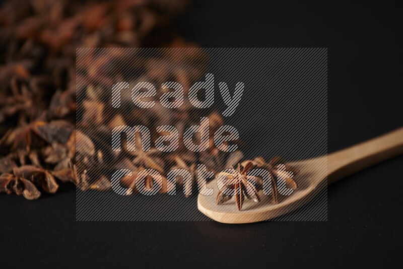 اليانسون النجمي في ملعقة خشبية ومتناثر على أرضية سوداء