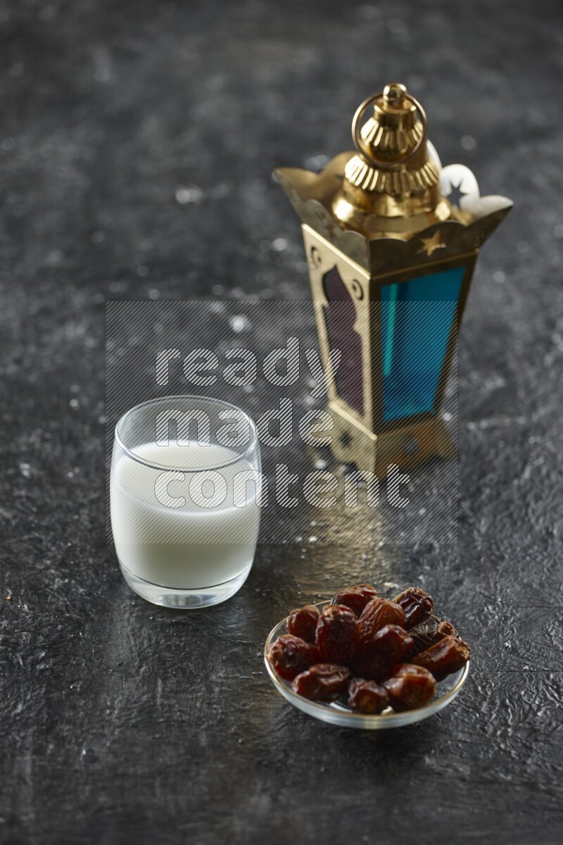 A golden lantern with different drinks, dates, nuts, prayer beads and quran on textured black background