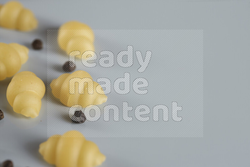 Raw pasta with different ingredients such as cherry tomatoes, garlic, onions, red chilis, black pepper, white pepper, bay laurel leaves, rosemary, cardamom and mushrooms on light blue background