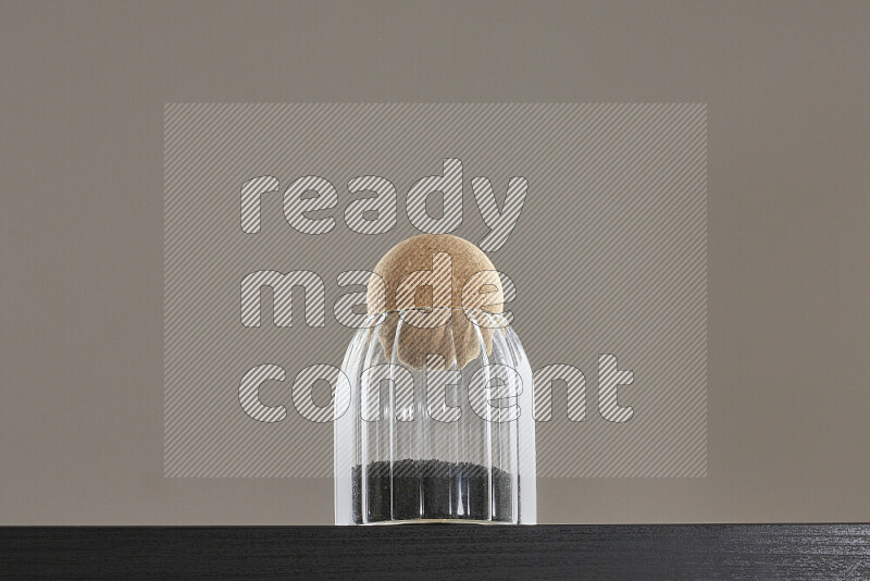 Black seeds in a glass jar on black background