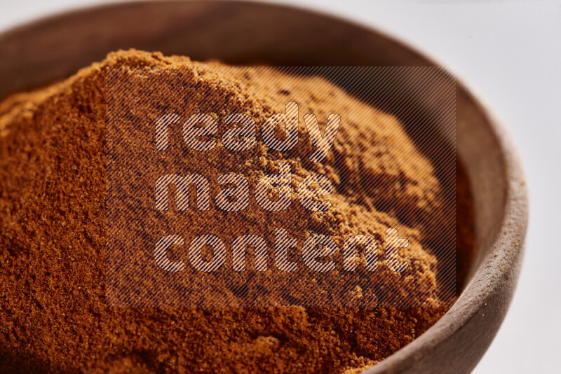 A wooden bowl full of ground paprika powder on white background