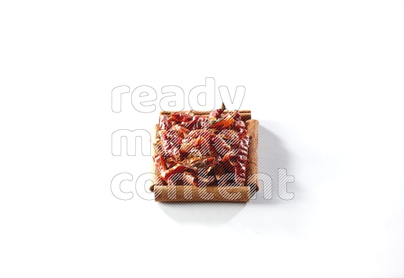 A single square of cinnamon sticks full of chilis on white flooring