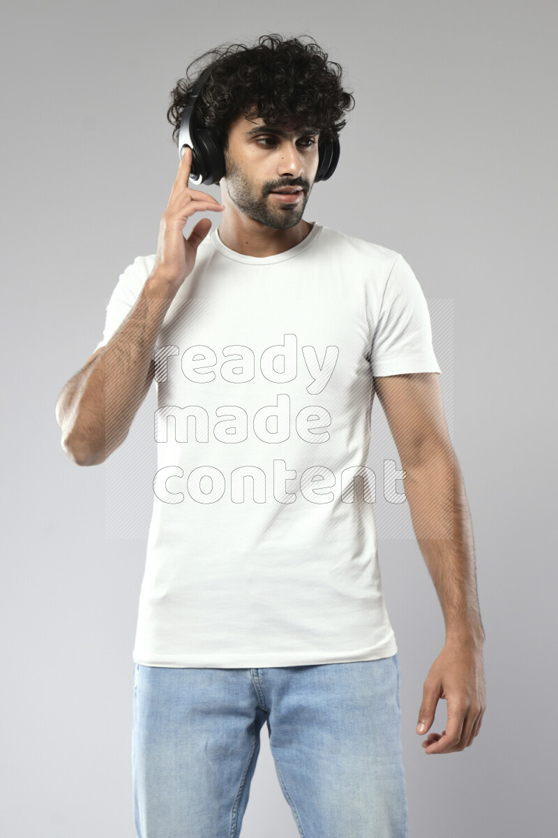 A man wearing casual standing and putting on headphones on white background