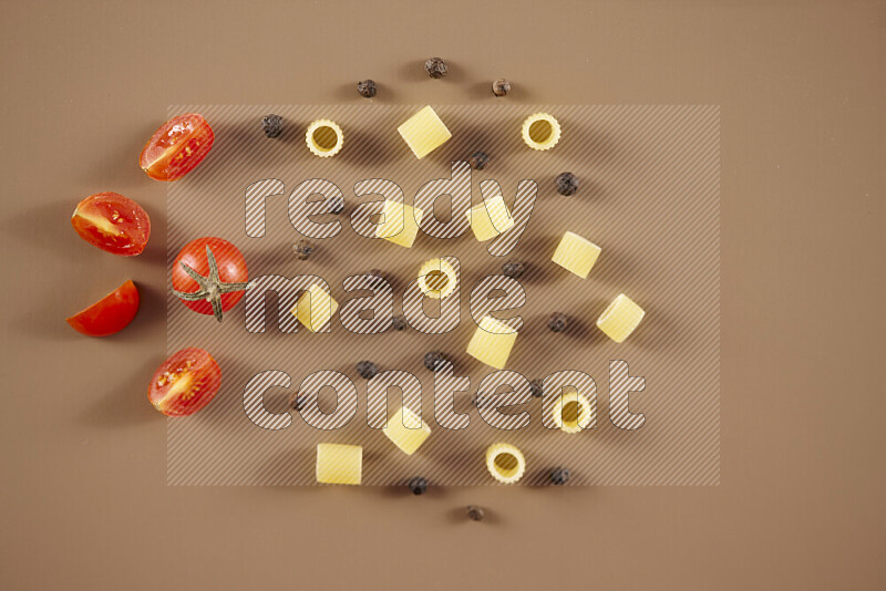 Raw pasta with different ingredients such as cherry tomatoes, garlic, onions, red chilis, black pepper, white pepper, bay laurel leaves, rosemary and cardamom on beige background