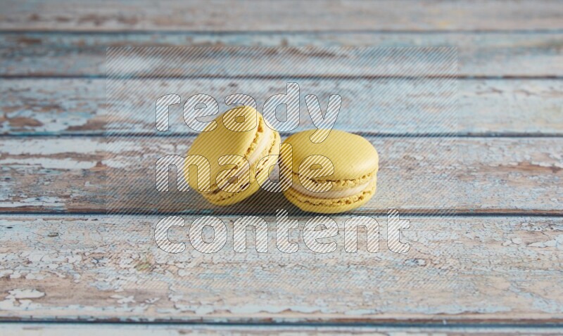 45º Shot of two Yellow Lime macarons on light blue wooden background