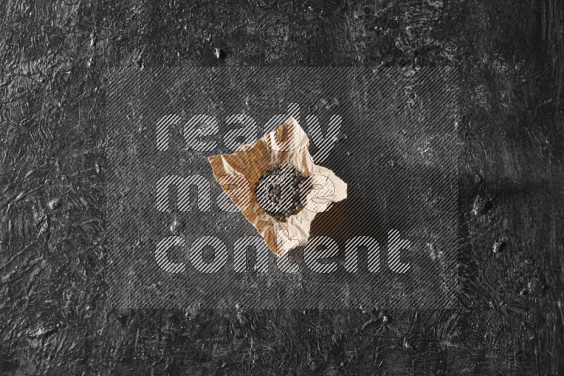 Black pepper beads on crumpled paper on a textured black flooring