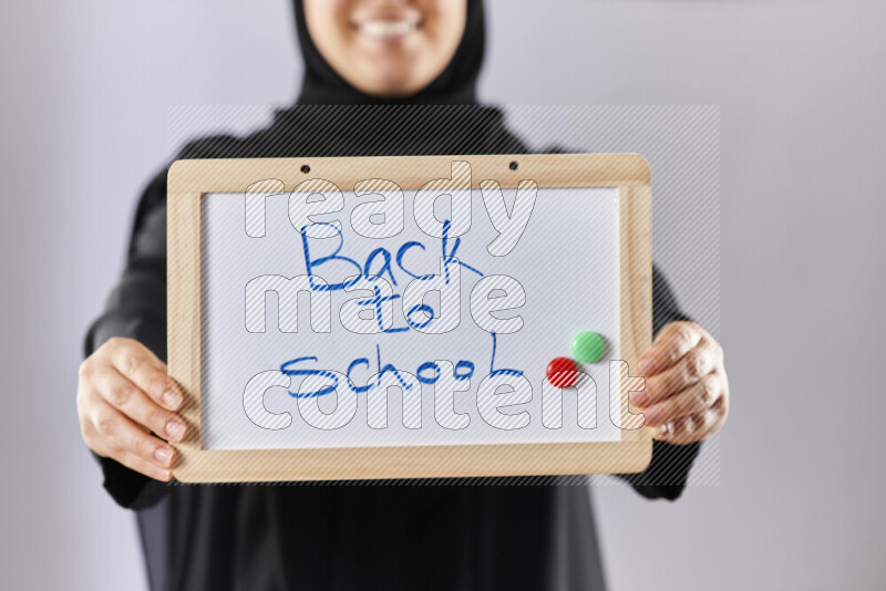 A woman in abaya holding books and a board in different positions (back to school)