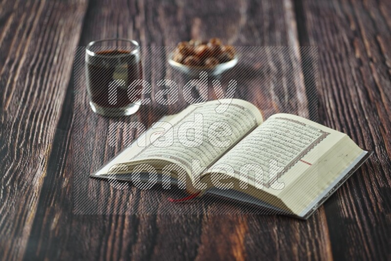 القرآن مع التمر وسبحة الصلاة ومشروبات مختلفة جميعها موضوعة على خلفية خشبية