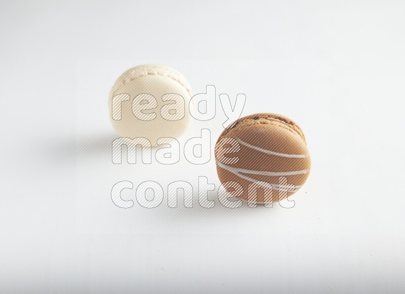 45º Shot of of two assorted Brown Irish Cream, and White Caramel fleur de sel macarons on white background