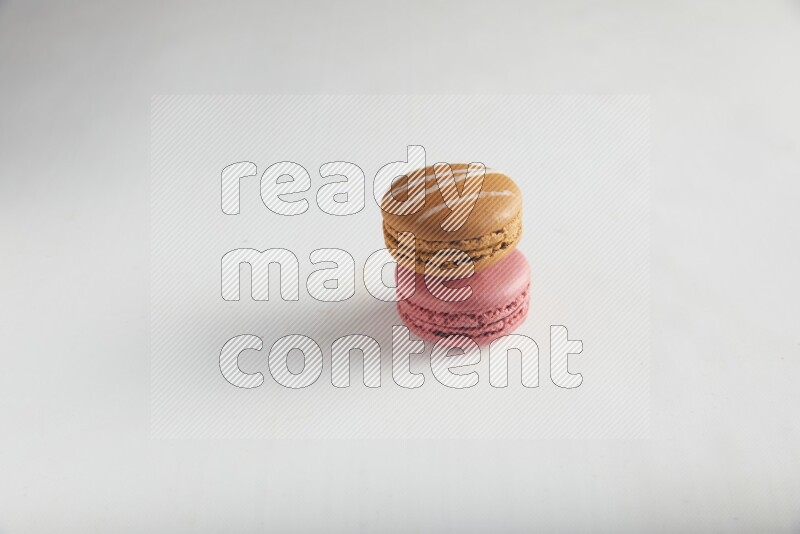 45º Shot of of two assorted Brown Irish Cream, and Pink Raspberry macarons on white background
