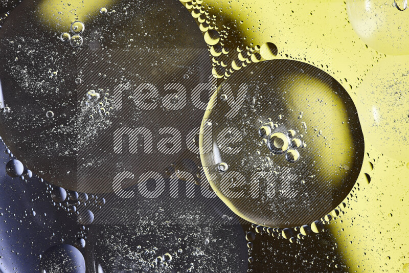 Close-ups of abstract oil bubbles on water surface in shades of black and yellow