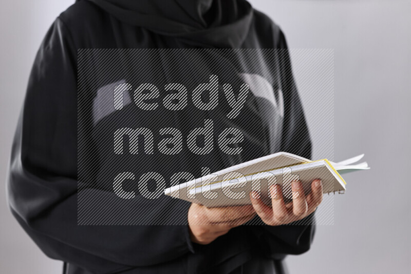 A woman in abaya holding books and a board in different positions (back to school)