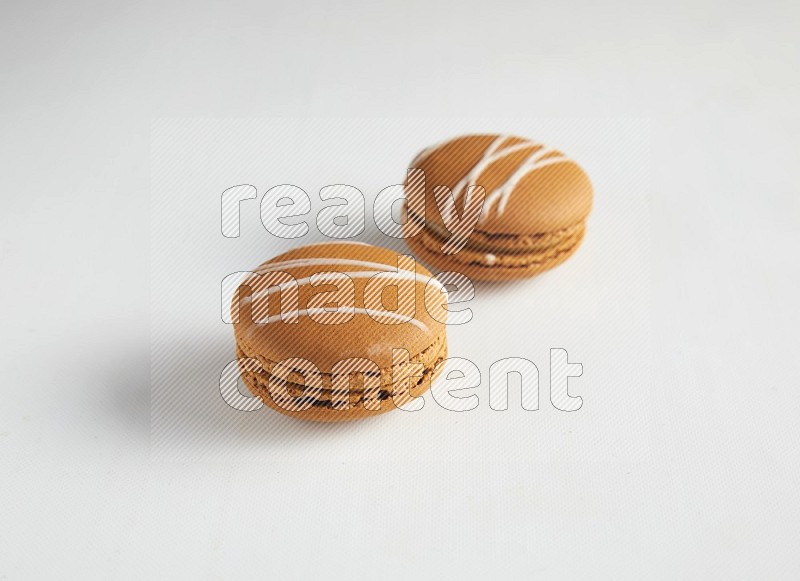 45º Shot of two Brown Irish Cream macarons on white background