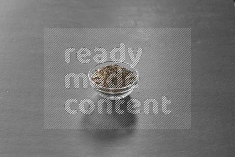 A glass bowl full of basil on black flooring